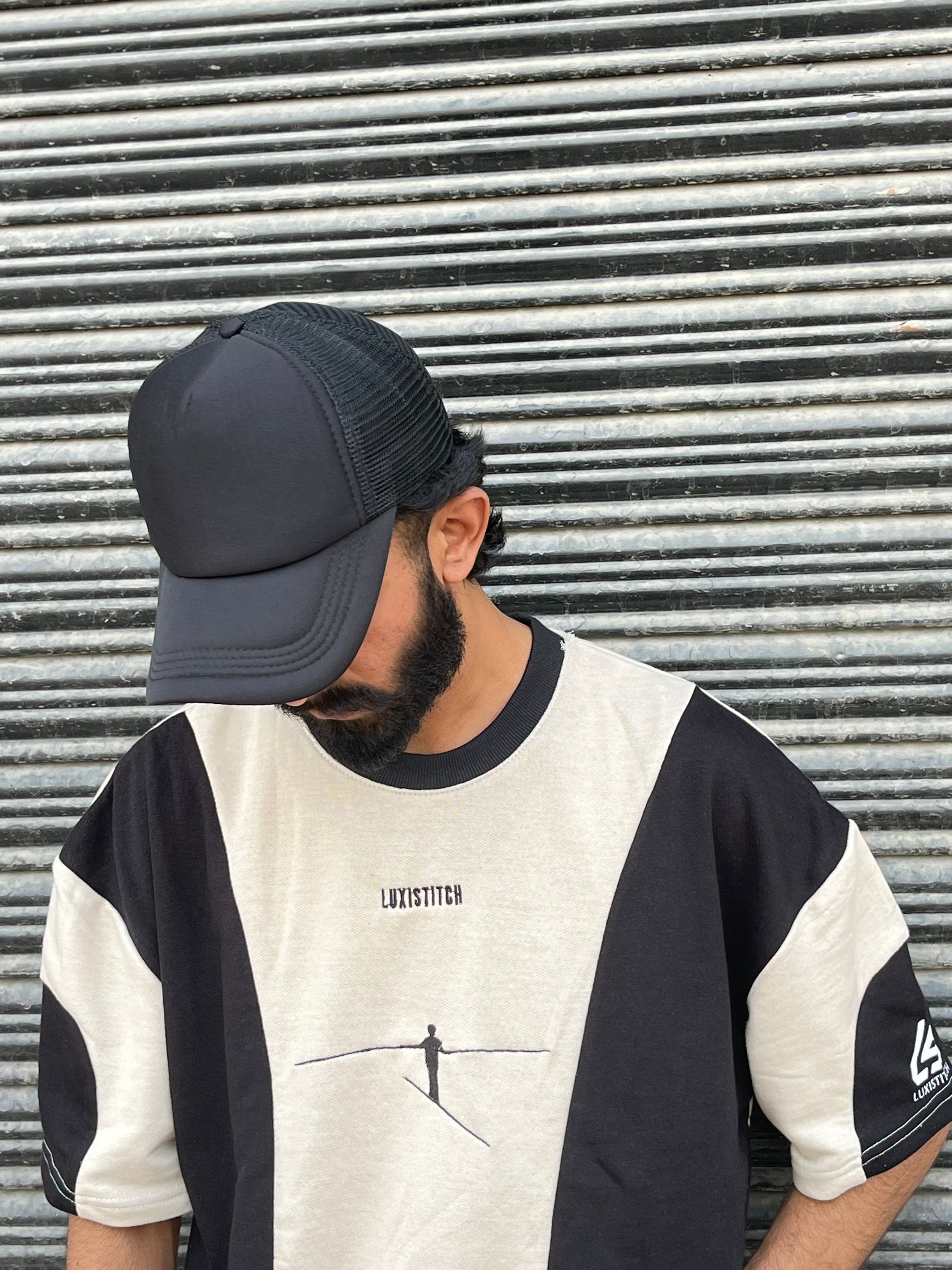 Man wearing a premium black trucker hat with mesh back and curved bill from LUXUSIO